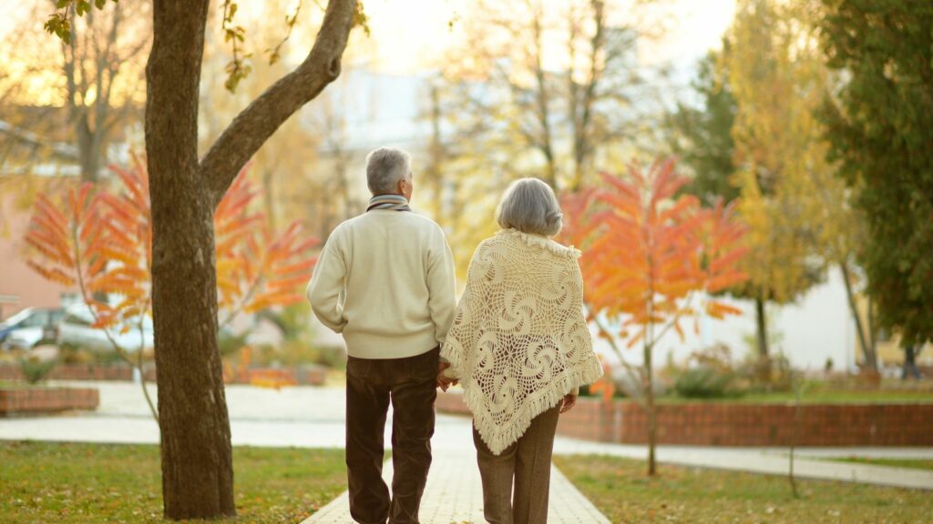 elderly couple walking through a park